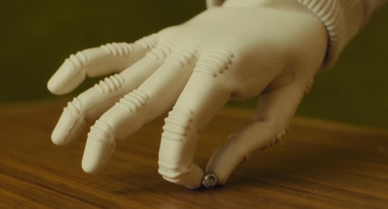 Close-up of a 1X NEO robot hand resting on a wooden table