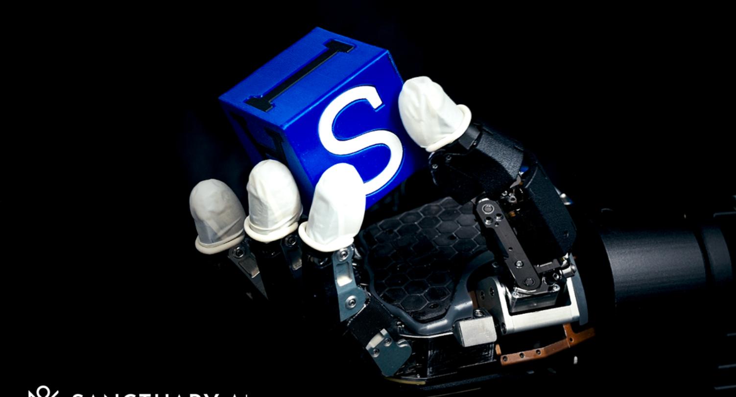 A Sanctuary AI hydraulic robot hand with white tactile fingertips holding a blue cube