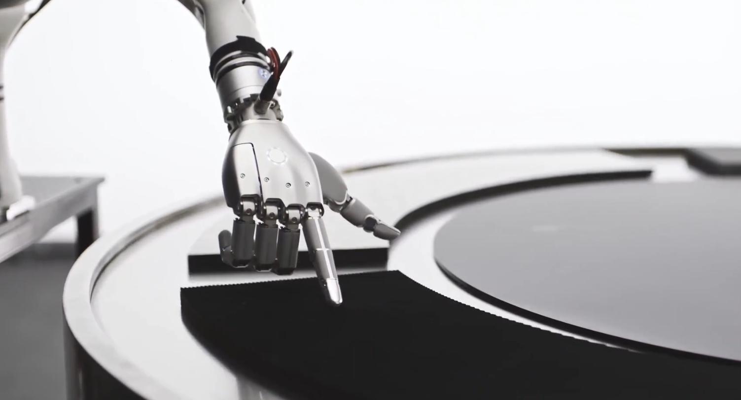 A SharpaWave robot hand on a robot arm touching a surface with one fingertip